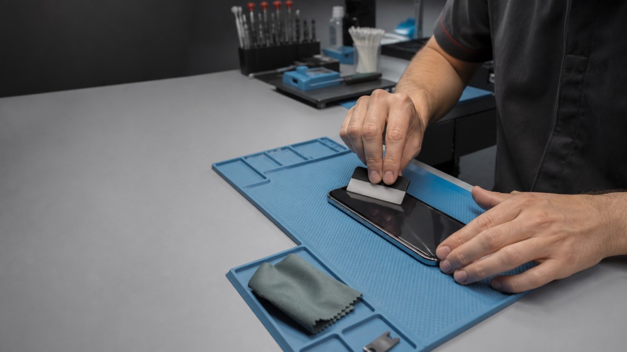 Technik nakładający folię ochronną na telefon na stanowisku PCDOCTOR w Białymstoku